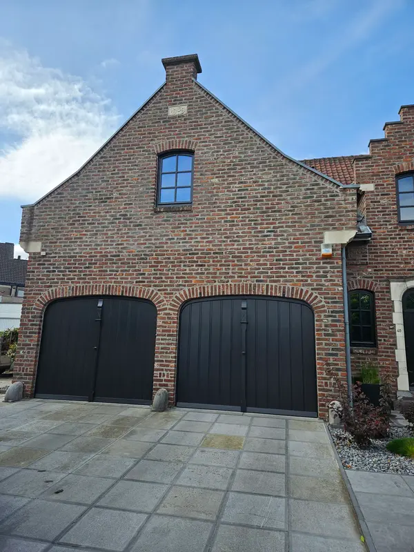 Bakstenen gevel met geschilderde garagedeuren en raamkozijn